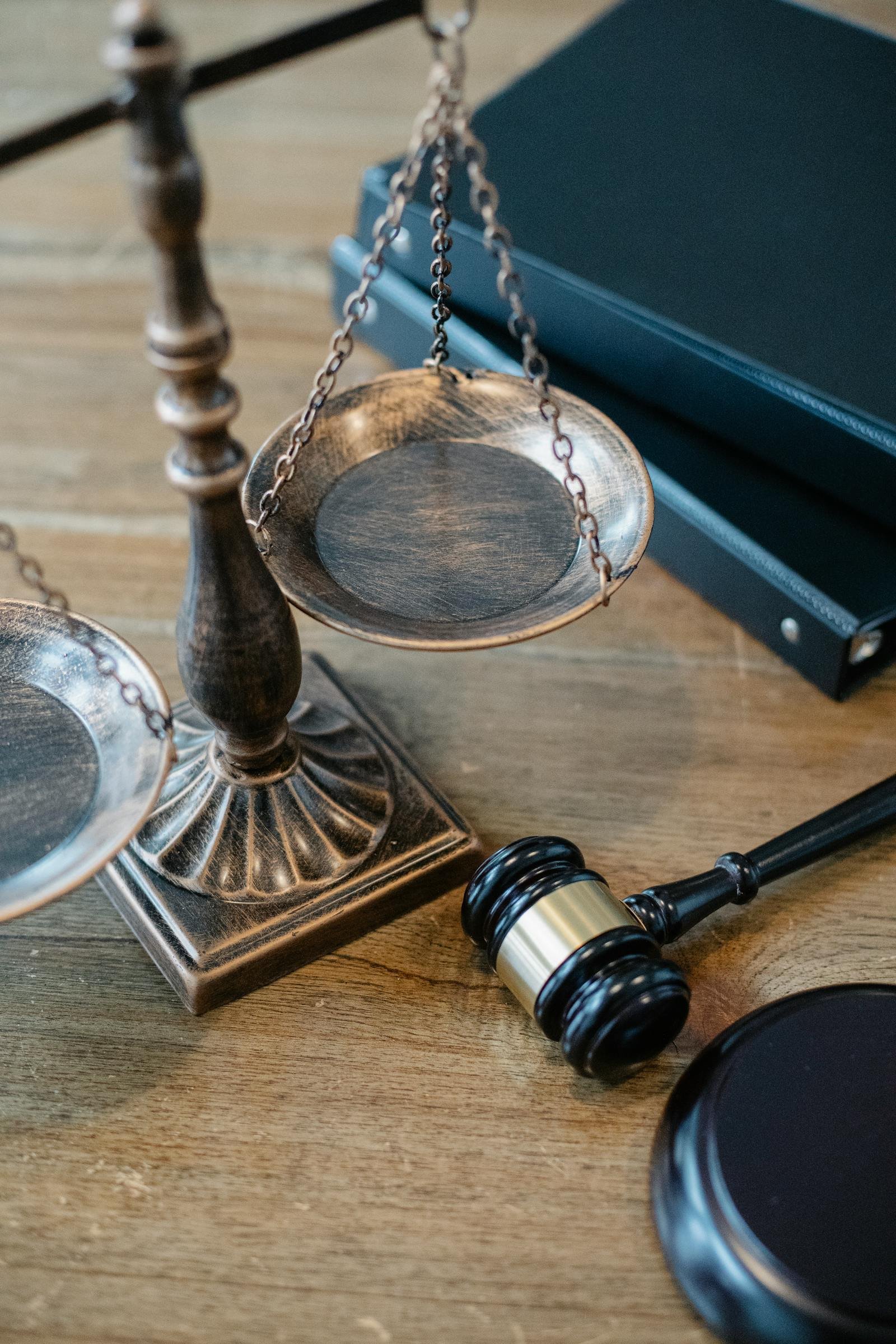 Bilancia della giustizia, codici giuridici e martelletto su scrivania in legno